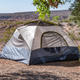 A small camp tent at the Las Vegas Bay Campground faced toward a desert valley with a large tree next to it.